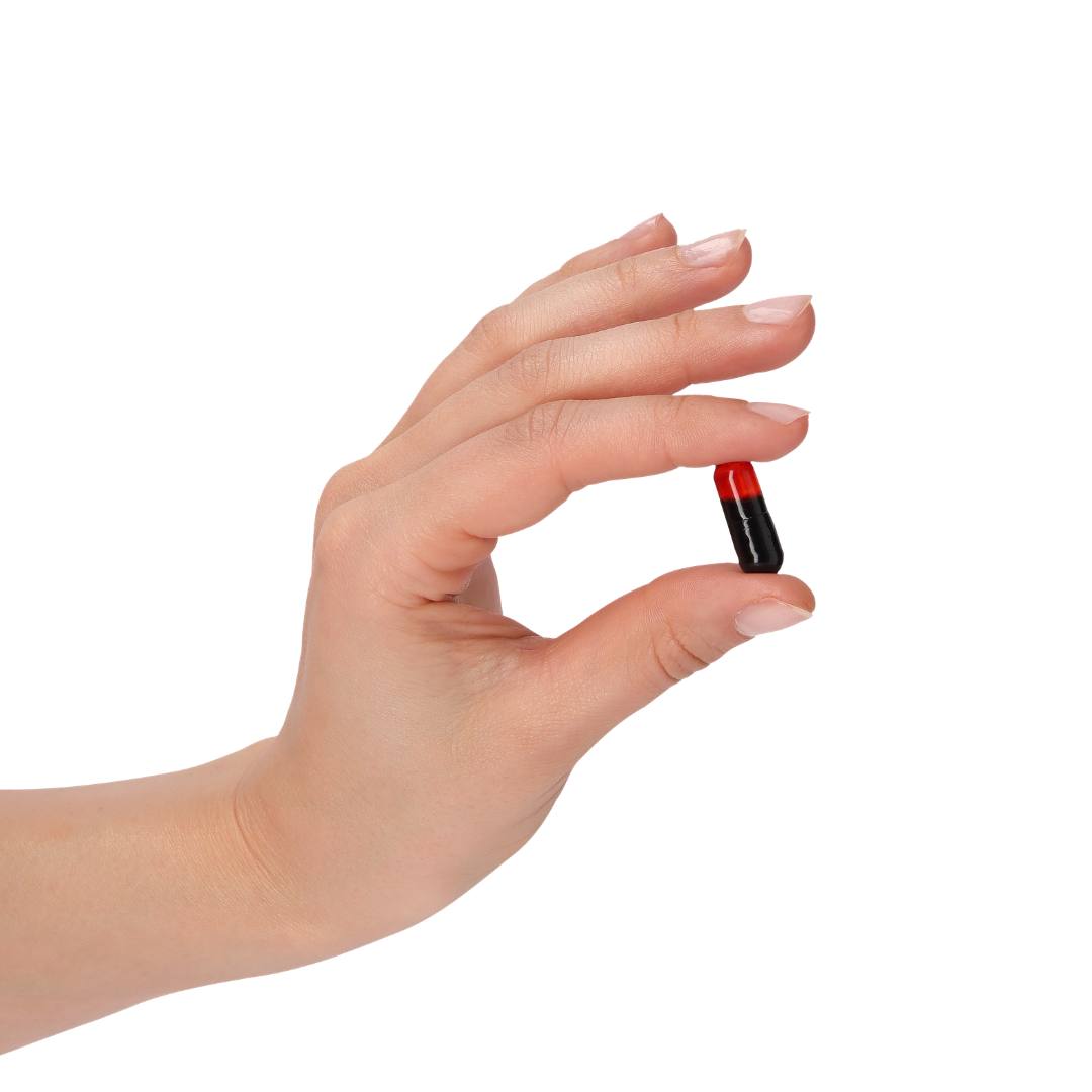 Hand hält eine vegane Omega-3 plus Astaxanthin Kapsel zwischen den Fingern