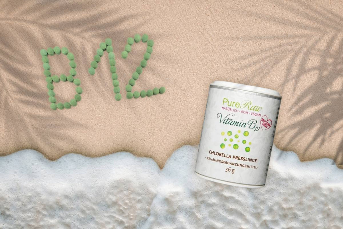 PureRaw Vitamin-B12-Chlorella-Presslinge am Strand, daneben ist „B12“ aus grünen Presslingen in den Sand gelegt.