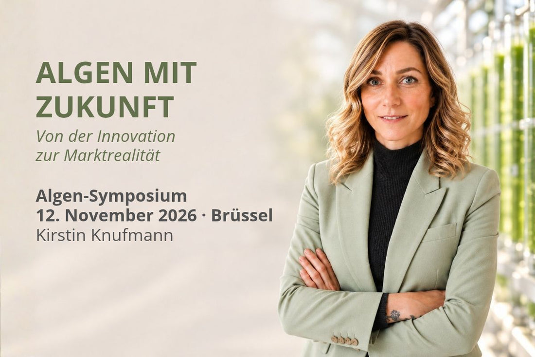 Kirstin Knufmann im hellgrünen Blazer vor grünen Glasröhren zur Algenkultivierung. Ankündigung ihrer Teilnahme als Referentin beim Algen-Symposium am 12. November 2026 in Brüssel.