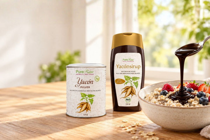 PureRaw Yacon-Sirup und Yacon-Pulver neben einer Frühstücksschale mit Apfel und Zimt; Sirup wird mit einem Löffel darübergegeben.