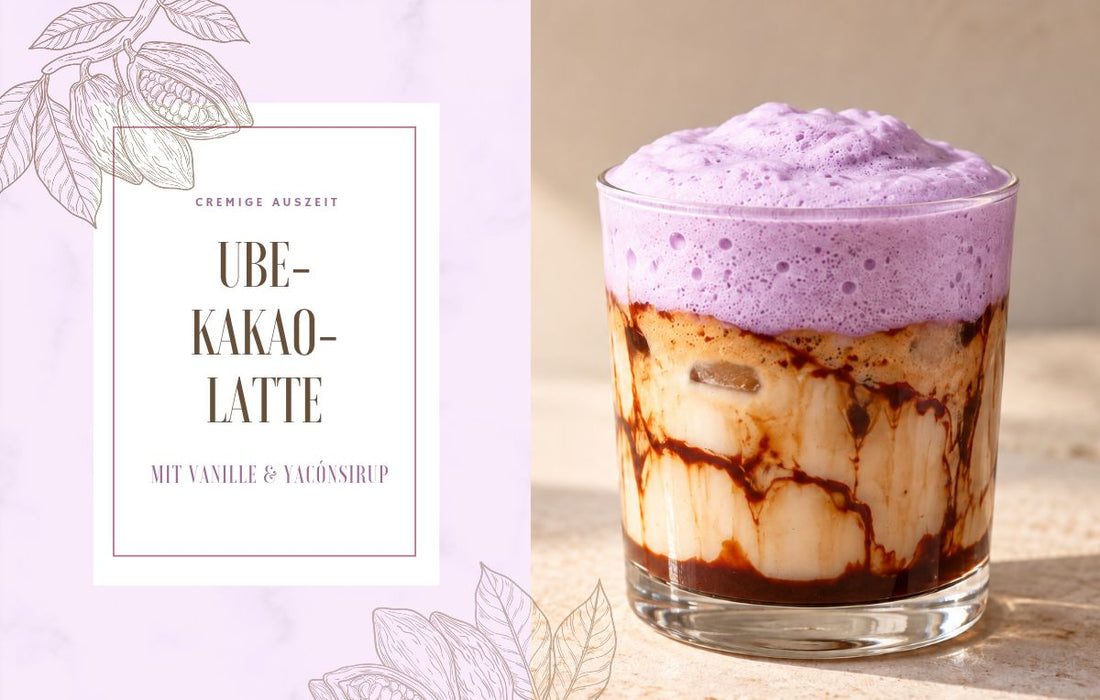 Ube-Kakao-Latte im Glas mit Kakao-Marmorierung, Eiswürfeln und helllila Ube-Vanille-Schaum auf einem hellen Steintisch.