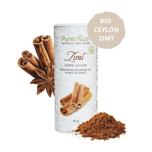 Produkt mit Gewürzen: PureRaw Bio-Ceylon-Zimtpulver neben Zimtstangen, Sternanis und einem Häufchen gemahlenem Zimt.