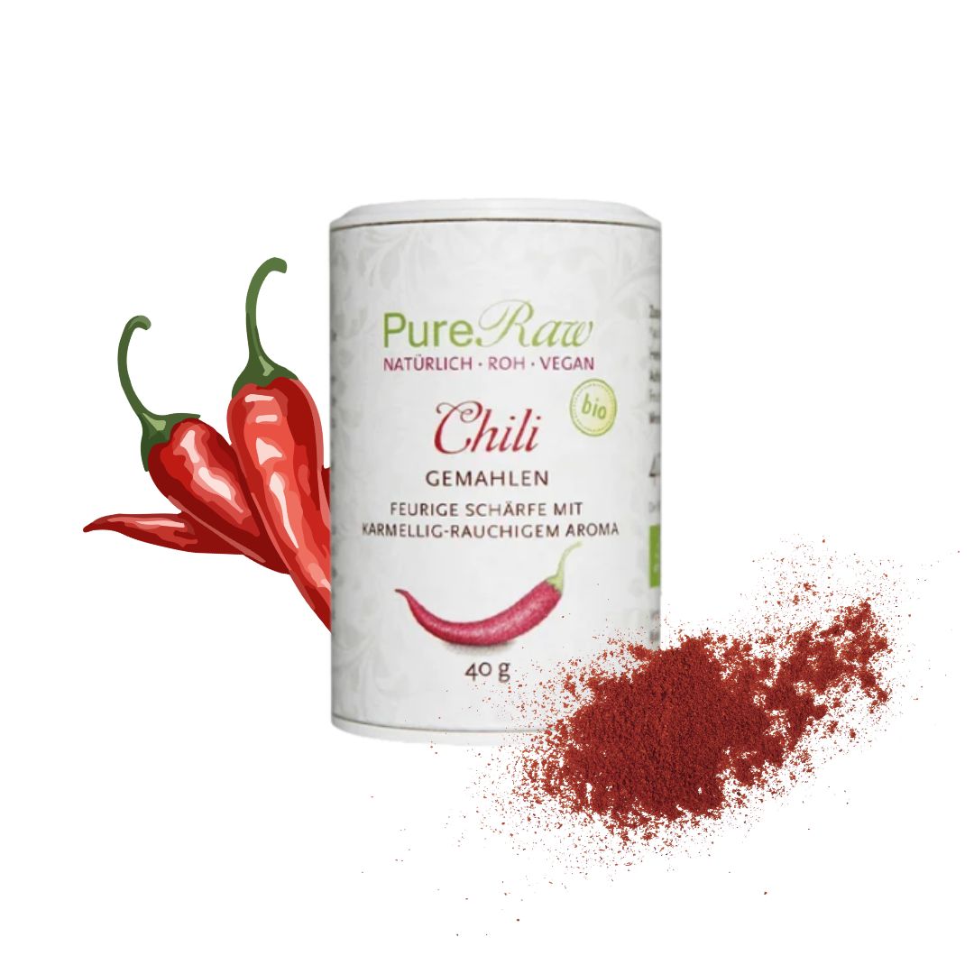 Produkt mit Chili: PureRaw Bio-Chilipulver in der Dose neben roten Chilischoten und fein gemahlenem Chilipulver.