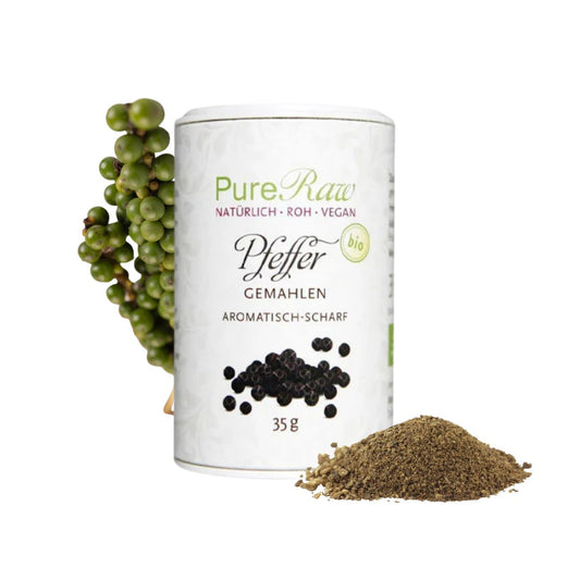 PureRaw Bio-Pfeffer in der 35-g-Dose neben einer grünen Pfefferrispe und einem Häufchen gemahlenem schwarzen Pfeffer.