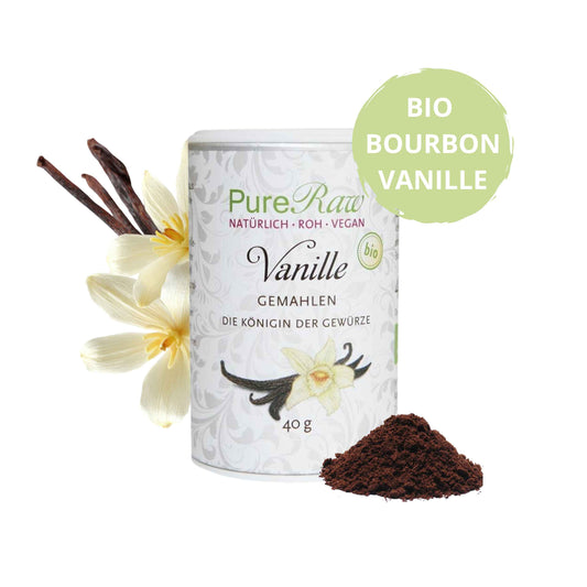 PureRaw Bio-Bourbon-Vanillepulver mit Vanilleschoten, Vanilleblüte und einem Häufchen gemahlener Vanille.
