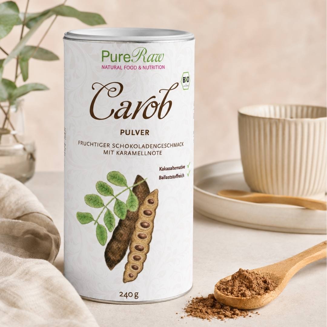 Eine Dose „PureRaw Carob Pulver“ neben einem Holzlöffel voller Carob Pulver