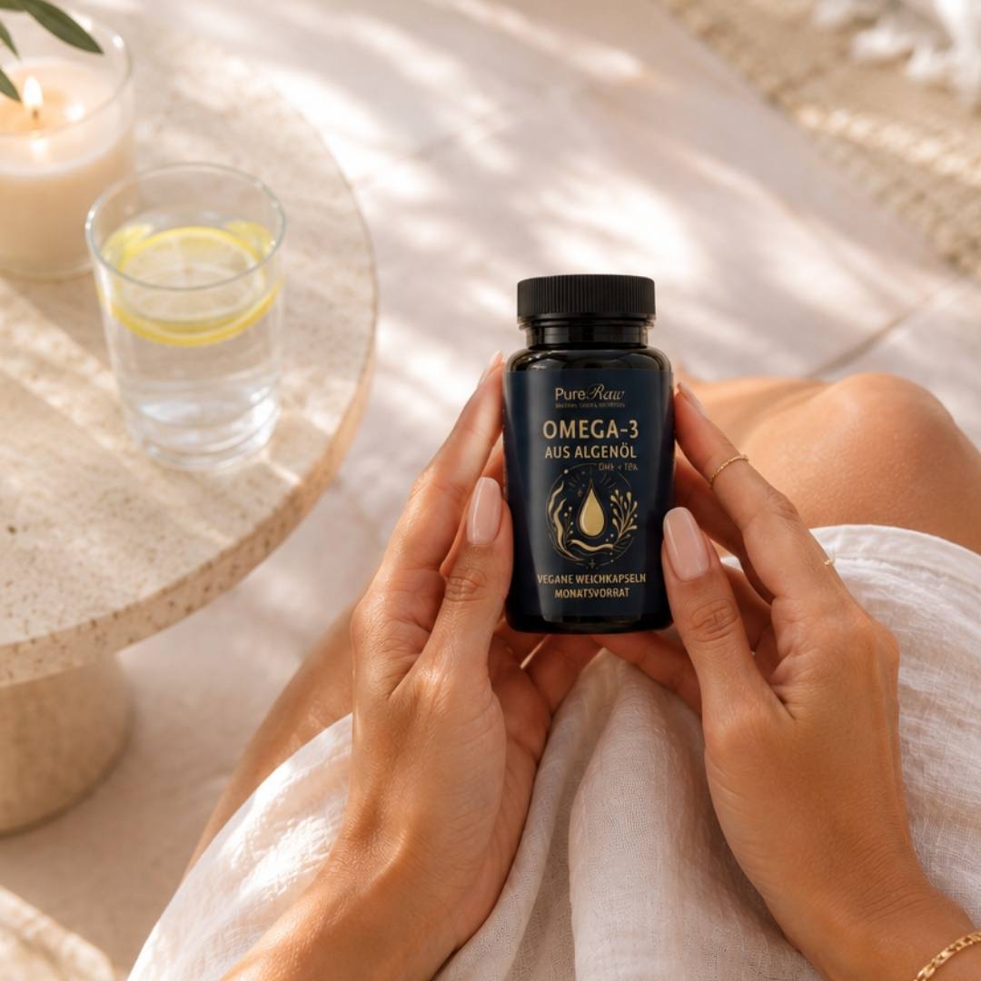 Hand hält PureRaw Omega-3 aus Algenöl neben einem Glas Wasser
