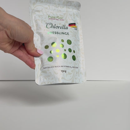 Video - Hand hält einen Beutel PureRaw Chlorella Presslinge vor hellem Hintergrund