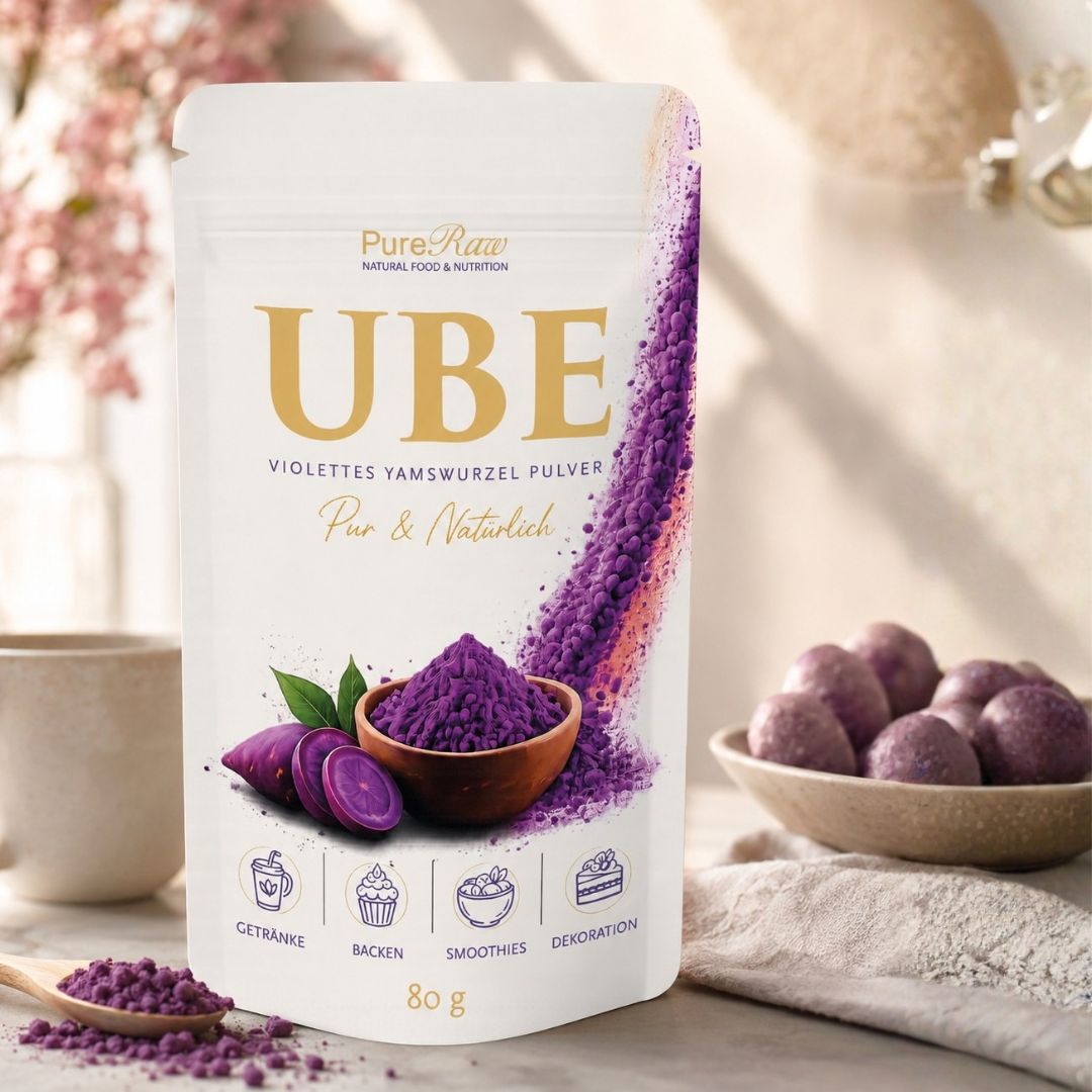 PureRaw Ube Pulver in einer hellen Küchenszene mit violettem Pulver in einer Schale und Yamswurzeln.