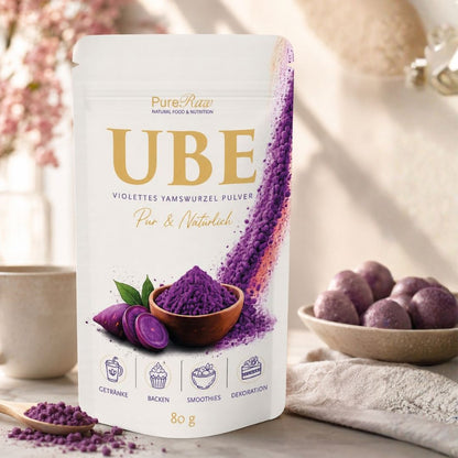 PureRaw Ube Pulver in einer hellen Küchenszene mit violettem Pulver in einer Schale und Yamswurzeln.